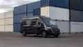 Das 20 Jahre Jubiläumsmodell von SUNLIGHT: Der Camper Van CLIFF 600 XX steht auf dem Asphalt vor mehreren Container